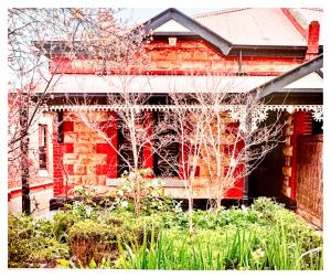 HAVEN: Stunning Unley *history*location*charm 3bd في Unley: منزل من الطوب الأحمر أمامه أشجار