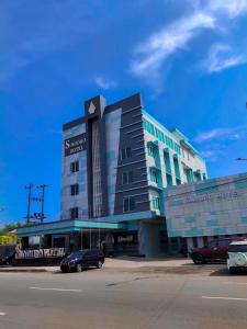a large building with cars parked in front of it at Sindoro Hotel Cilacap By Conary in Cilacap