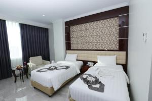 a hotel room with two beds and a chair at Sindoro Hotel Cilacap By Conary in Cilacap
