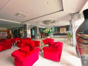 a living room with red chairs and a table at Sindoro Hotel Cilacap By Conary in Cilacap