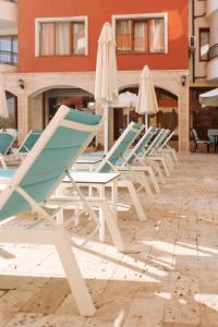 a row of lounge chairs and umbrellas on a patio at Apartment Complex Rich in Nesebar