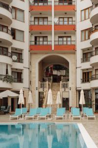een zwembad tegenover een hotel met stoelen en parasols bij Apartment Complex Rich in Nesebar