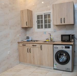 a kitchen with a washing machine and a microwave at Vital House Apartments شقق البيت الحيوي in Jeddah