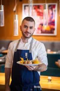 a man in a kitchen holding a plate of food at HVD Grand Hotel Suhl Business & Leisure in Suhl