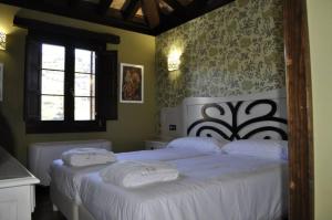een slaapkamer met 2 bedden met witte lakens en een raam bij Hotel Rural El Reundu in Campomanes