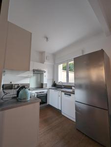 uma cozinha com armários brancos e um frigorífico de aço inoxidável em Maison Luxe avec Jardin, 5 Chambres, Home Cinéma - Métro 1 em Vincennes