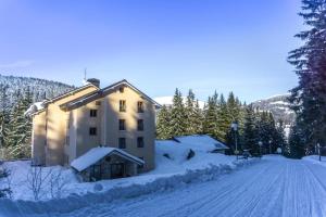 a building covered in snow on a snowy road at Apartmán C01 Poustevník in Pec pod Sněžkou