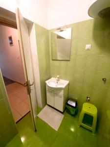 Baño verde con lavabo y espejo en Crazy House Hostel, en Pula