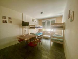 um quarto com uma mesa, cadeiras e beliches em Crazy House Hostel em Pula