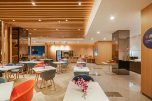 a restaurant with tables and chairs and a kitchen at Holiday Inn Express Shanghai Xuhui Binjiang, an IHG Hotel in Shanghai
