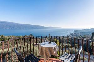 uma mesa e cadeiras numa varanda com vista para o oceano em Appartamento Arlecchino em Gargnano