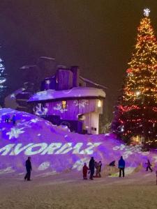 a christmas tree in front of a building with people at Spacious Stylish apartment for 8 by Avoriaz Chalets in Avoriaz