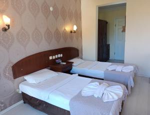 een slaapkamer met 2 bedden en een spiegel bij Grand Cnr Hotels in Fethiye