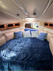 a bed in the back of a rv with blue pillows at Maser II ( Excelente Mini Yate ) in Valencia