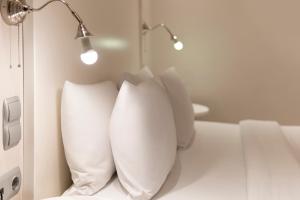 a row of pillows on a bed with a lamp at Piraeus City Hotel in Piraeus