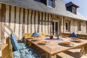 een houten tafel met blauwe kussens op een patio bij Gîte le Terrier in Hotot-en-Auge