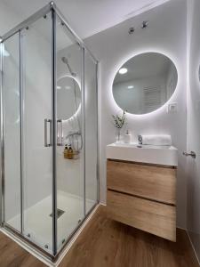 y baño con ducha acristalada y lavamanos. en Numancia Suites en Soria