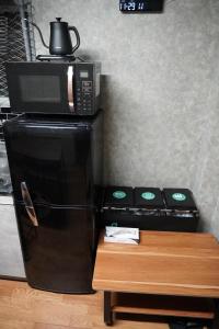 een magnetron bovenop een zwarte koelkast bij 駅から徒歩4分/ビル3階全体/広い部屋/広い屋上/和室/レインボーブリッジ/お台場 in Tokyo