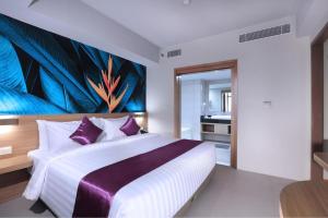 a bedroom with a large bed with a painting on the wall at Quest Prime Cikarang by ASTON in Bekasi