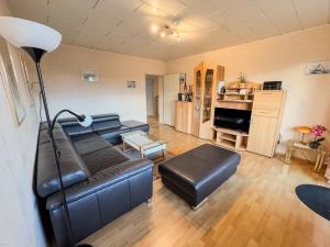 ein Wohnzimmer mit einem Ledersofa und einem Tisch in der Unterkunft Ferienwohnung Ankommen & Wohlfühlen in Cuxhaven