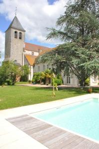a person standing next to a swimming pool in front of a church at Le Prieuré Saint Agnan in Cosne-Cours-sur-Loire