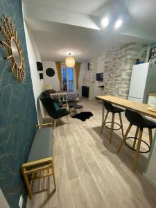 - un salon avec une table, des chaises et un mur en pierre dans l'établissement Charmant studio idéalement placé et paisible !, à Oloron-Sainte-Marie