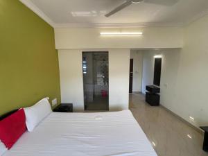 um quarto com uma cama branca e uma almofada vermelha em Hotel kumar em Panchgani