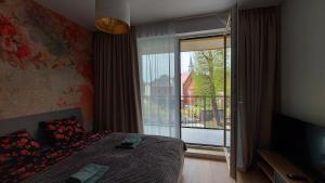 a bedroom with a bed and a large window with a balcony at STARE MIASTO KWIATY in Elblag