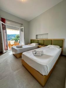 a bedroom with two beds and a balcony at Kavos Hotel in Patitiri