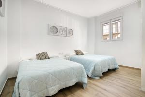Duas camas num quarto com paredes brancas e pisos em madeira em Gandia Confort Lope de Vega em Gandia