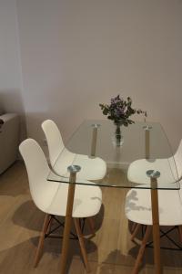 a glass table with white chairs and a vase of flowers at Apartamento centro Santander in Santander