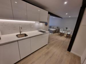 a kitchen with white cabinets and a living room at Apartamento centro Santander in Santander