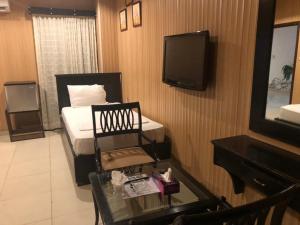 a room with a bed and a television and a table at silk.hotel in Faisalabad