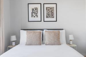 a bedroom with a white bed with two pictures on the wall at Dumbo 1br w gym roof nr TimeOut Building NYC-958 in Brooklyn