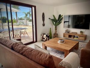 een woonkamer met een bank, een tafel en een televisie bij Off-grid Luxury Villa with Tikibar by the pool. in Calpe
