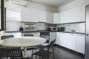 a kitchen with white cabinets and a table and chairs at [Piazza Goldoni] Suite Mazzini *Free WiFi* in Trieste