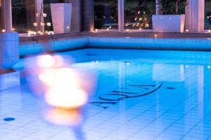 een persoon die 's nachts langs een zwembad loopt bij Trihotel Rostock - Wellnesshotel Adults Only in Rostock