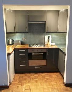 una cucina con armadi neri e piano cottura. di Victoria Park 1 bedroom flat a Londra
