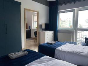 a bedroom with two beds and a television and a window at Apartament Black in Pasłęk