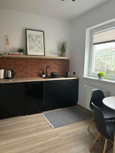 cocina con fregadero, mesa y ventana en Apartament Black, en Pasłęk