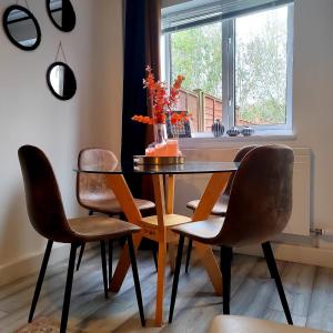 a dining room table with chairs and a vase with flowers at 2 Bedroom House in Quiet Area, Close to M5 With Free Parking by Glos Homes Ltd in Gloucester