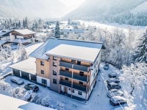 un immeuble dans la neige avec des voitures garées dans l'établissement Haus Kristall, à Tannheim