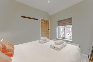 a white bedroom with two white towels on a bed at 3 Mill Street - Norfolk Cottage Agency in Holt