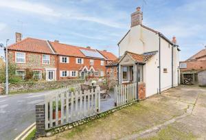 a white house with a fence next to a street at 3 Mill Street - Norfolk Cottage Agency in Holt