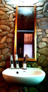 a bathroom sink with a mirror on a stone wall at Dreamer Resort in San Vicente