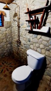 a bathroom with a white toilet and a stone wall at Dreamer Resort in San Vicente