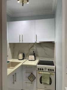 a white kitchen with a stove and white cabinets at Syntagma Hideaway Luxury Apt in Athens +10 photos