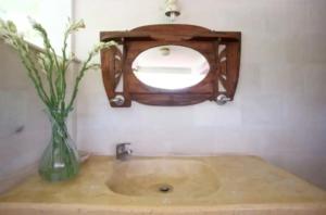 un lavandino in bagno con specchio e vaso di fiori di Abalone Sport Resort a Manggis Altre 10 foto