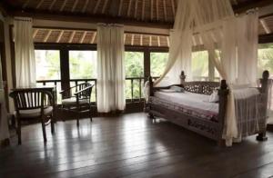 una camera con letto a baldacchino, sedie e finestre di Abalone Sport Resort a Manggis