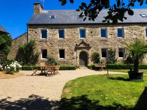 an old stone house with a table and chairs at Gîte du Triskell Le Domaine de Coat Rogan in Pommerit-Jaudy